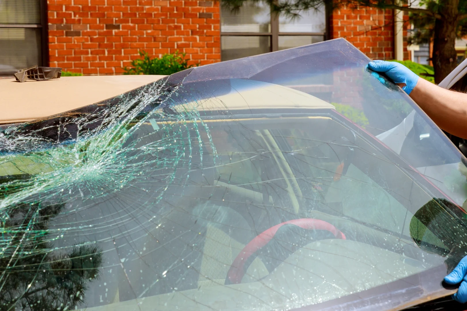Technician replacing a cracked car windshield with a new one.